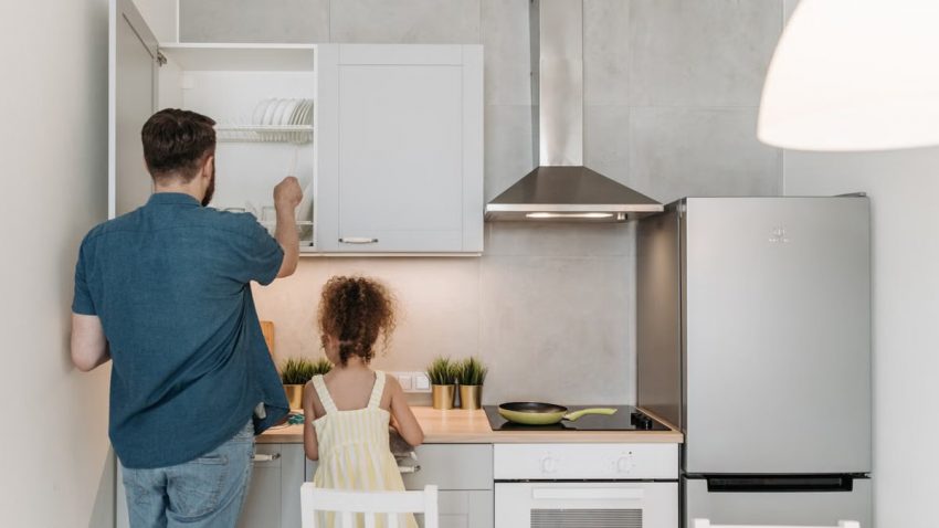 A father and daughter bonding while preparing a meal in a modern kitchen.